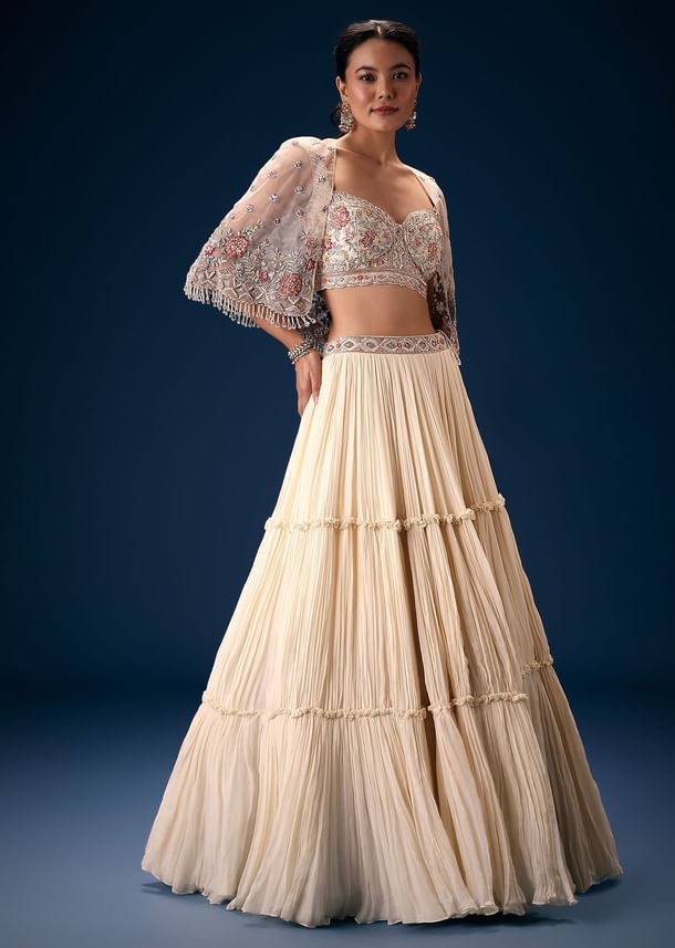 Off White Tiered Lehenga With Embroidered Corset Blouse And Embroidered Cape